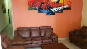 Ein Wohnzimmer mit braunem Ledersofa, einem Couchtisch und einer Wand mit einem farbenfrohen abstrakten Gemälde.