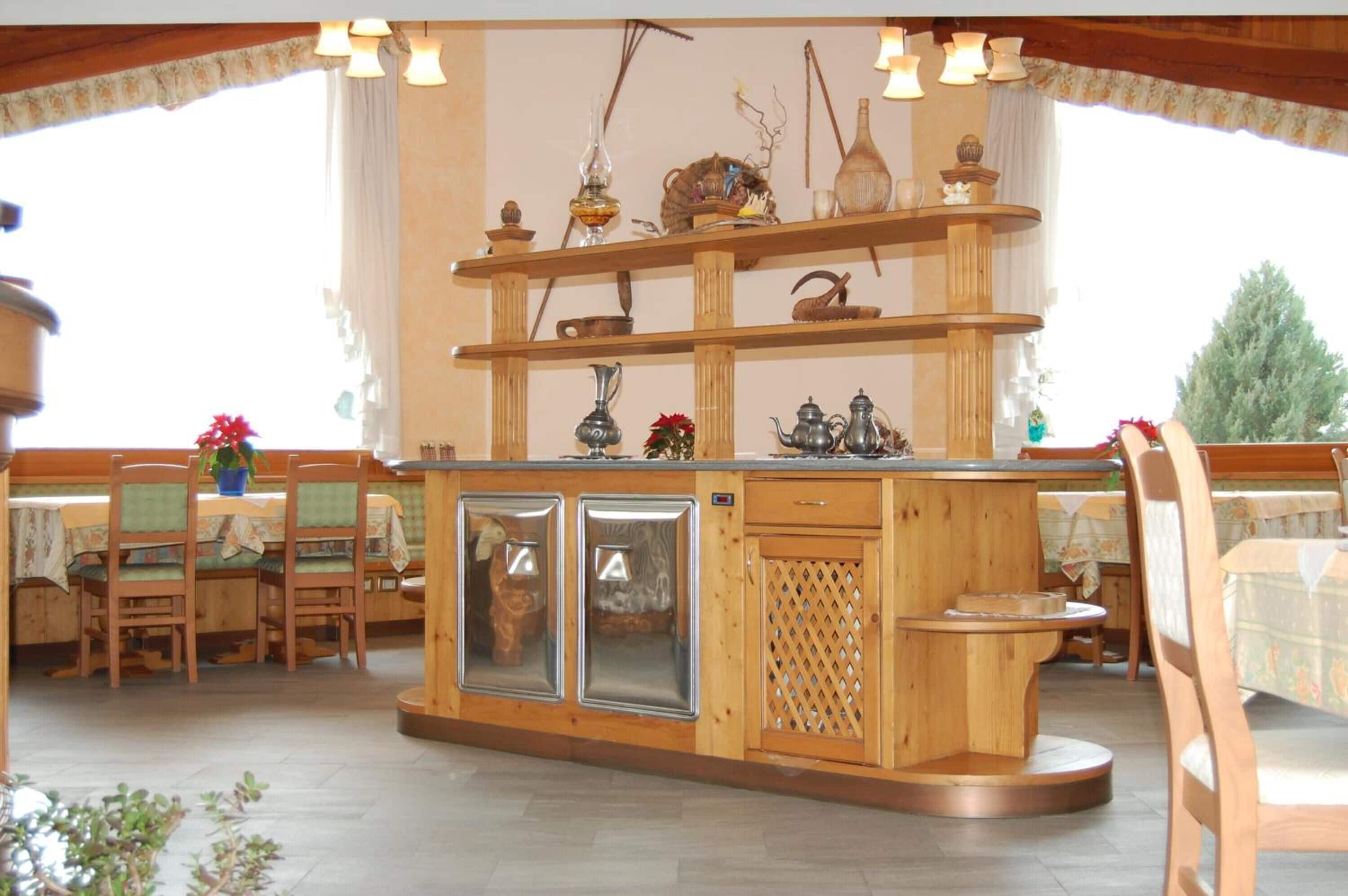 A wooden interior with a central counter, chairs, and tables.