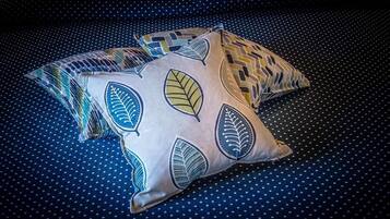 Trois coussins ornés de motifs de feuilles sur un tissu bleu foncé à pois.