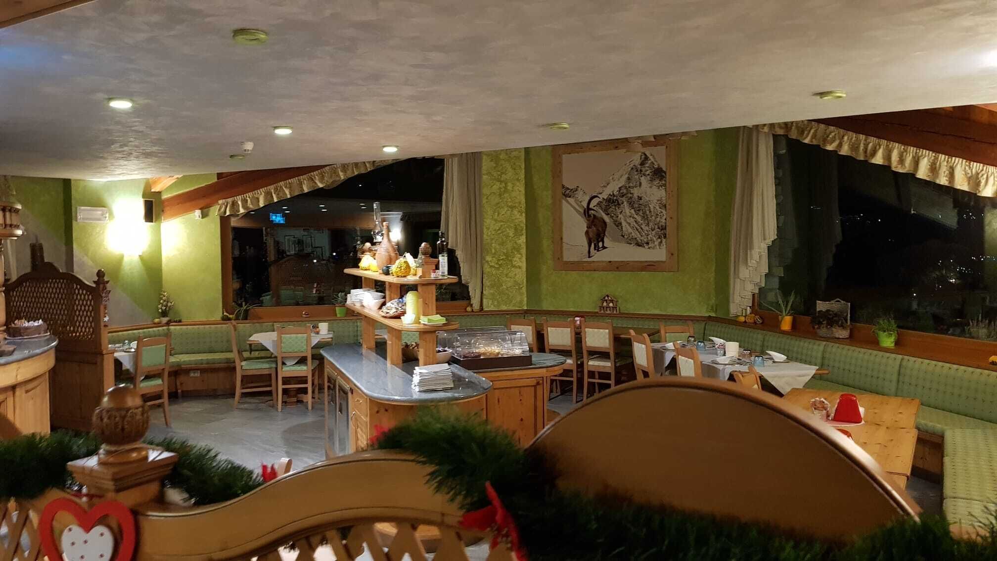 Un restaurante acogedor con barra, paredes verdes y un cuadro grande de un paisaje montañoso.