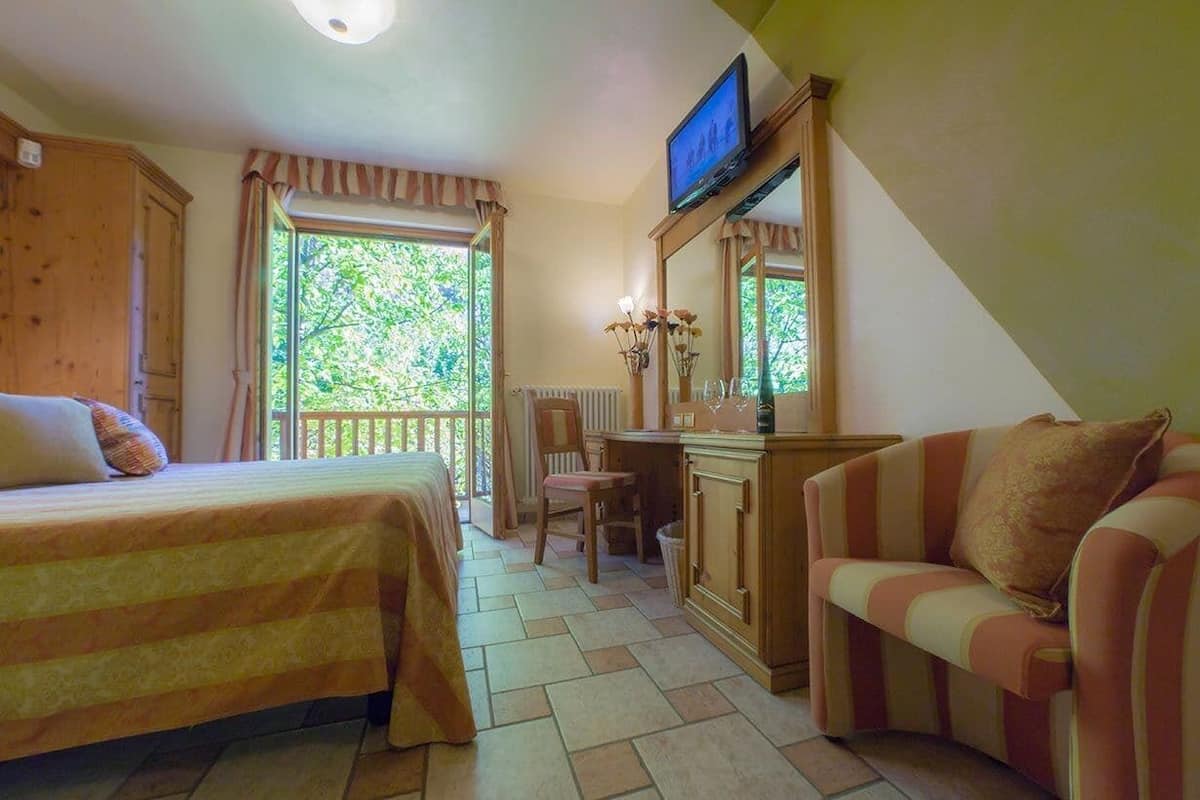 Un dormitorio con cama, escritorio, silla y televisor.