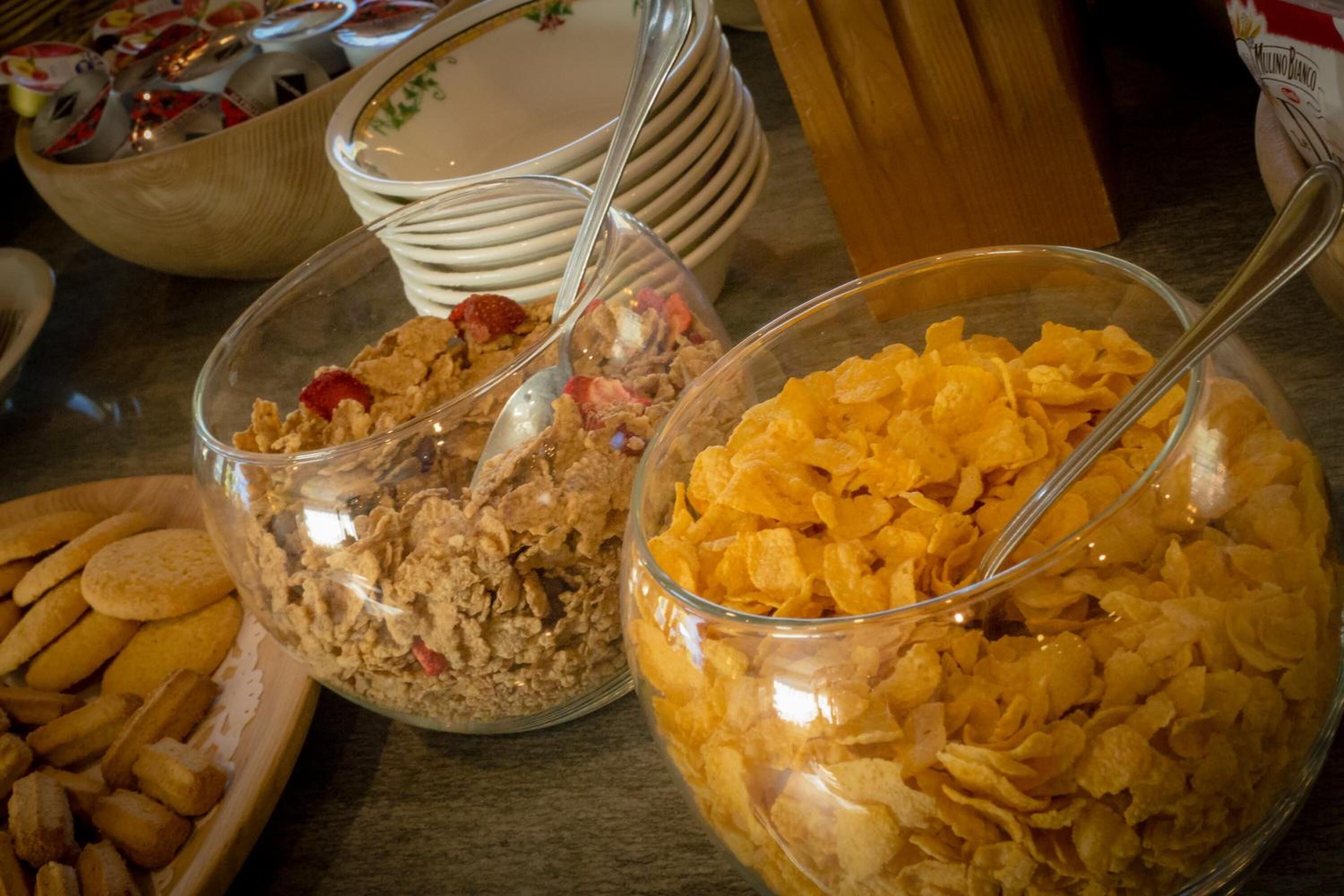 A buffet table with various food items including cereal, cookies, and a bowl of orange cereal.