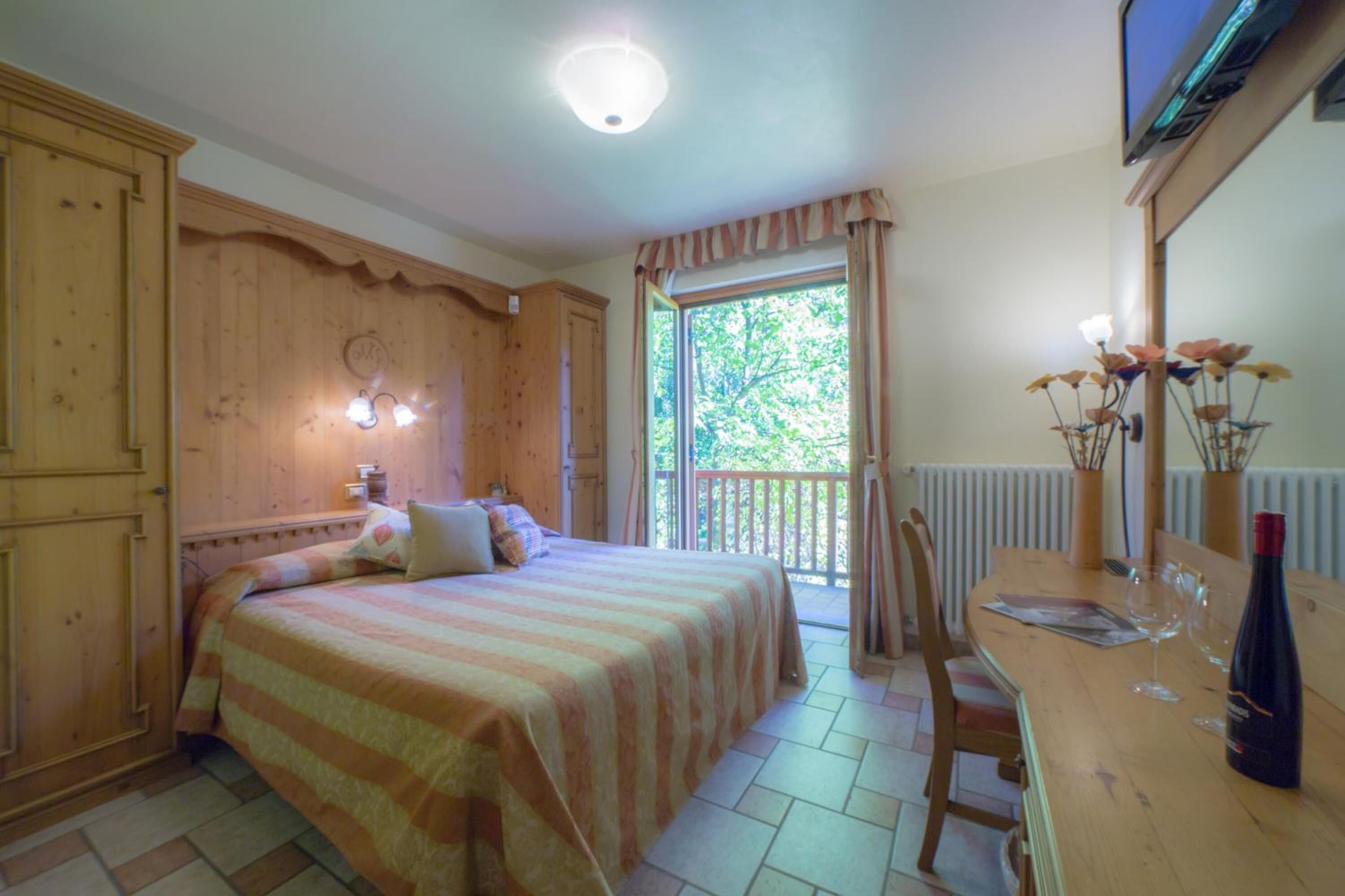 A room with a bed, a wooden table with chairs, a window with curtains, and a radiator.