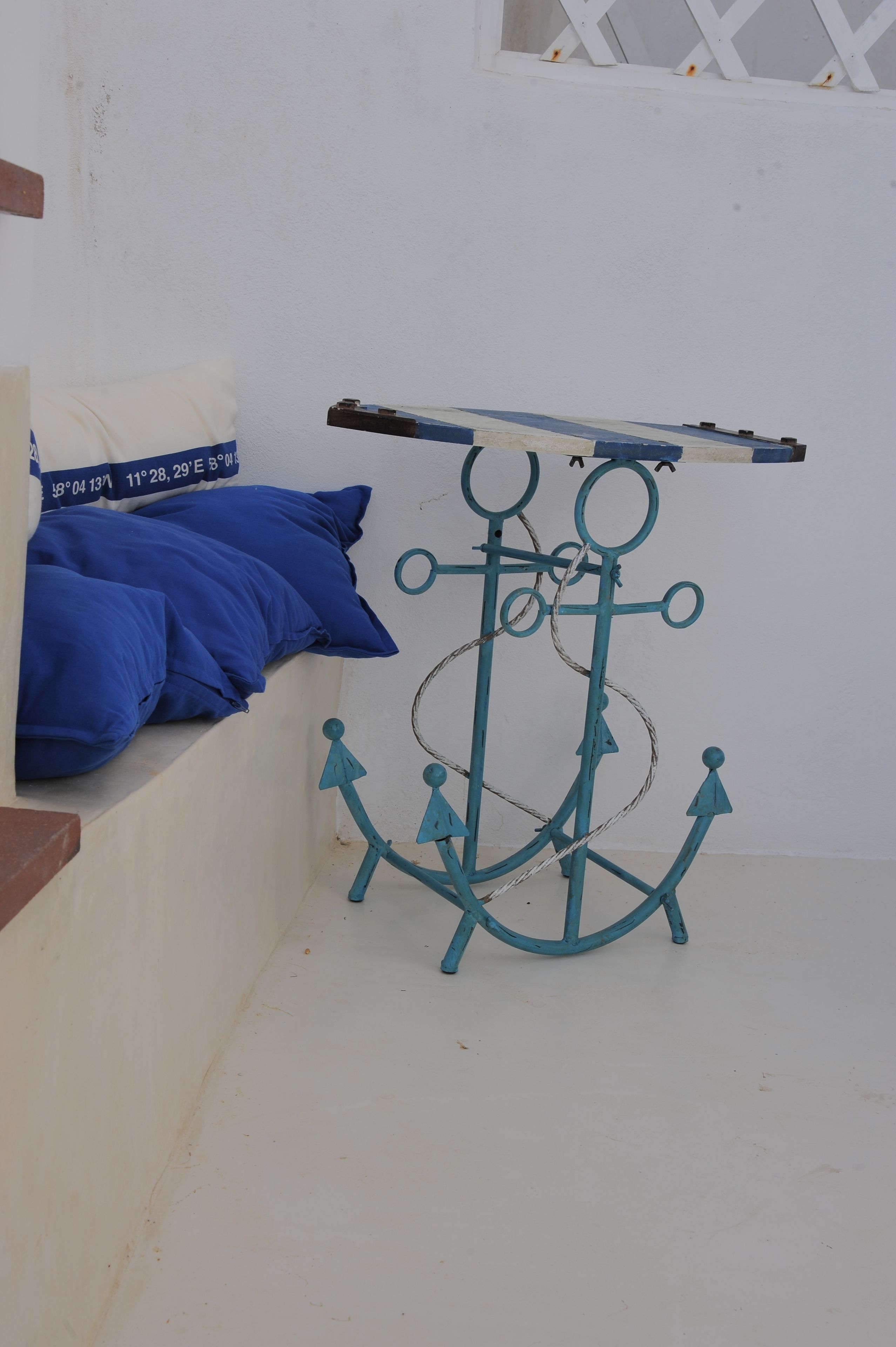 A corner with a white wall, a blue pillow, and a teal anchor-shaped rack.