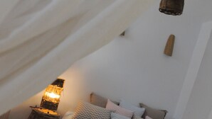 Een gezellige slaapkamer met een bed, kussens, een lamp en een geweven mand.