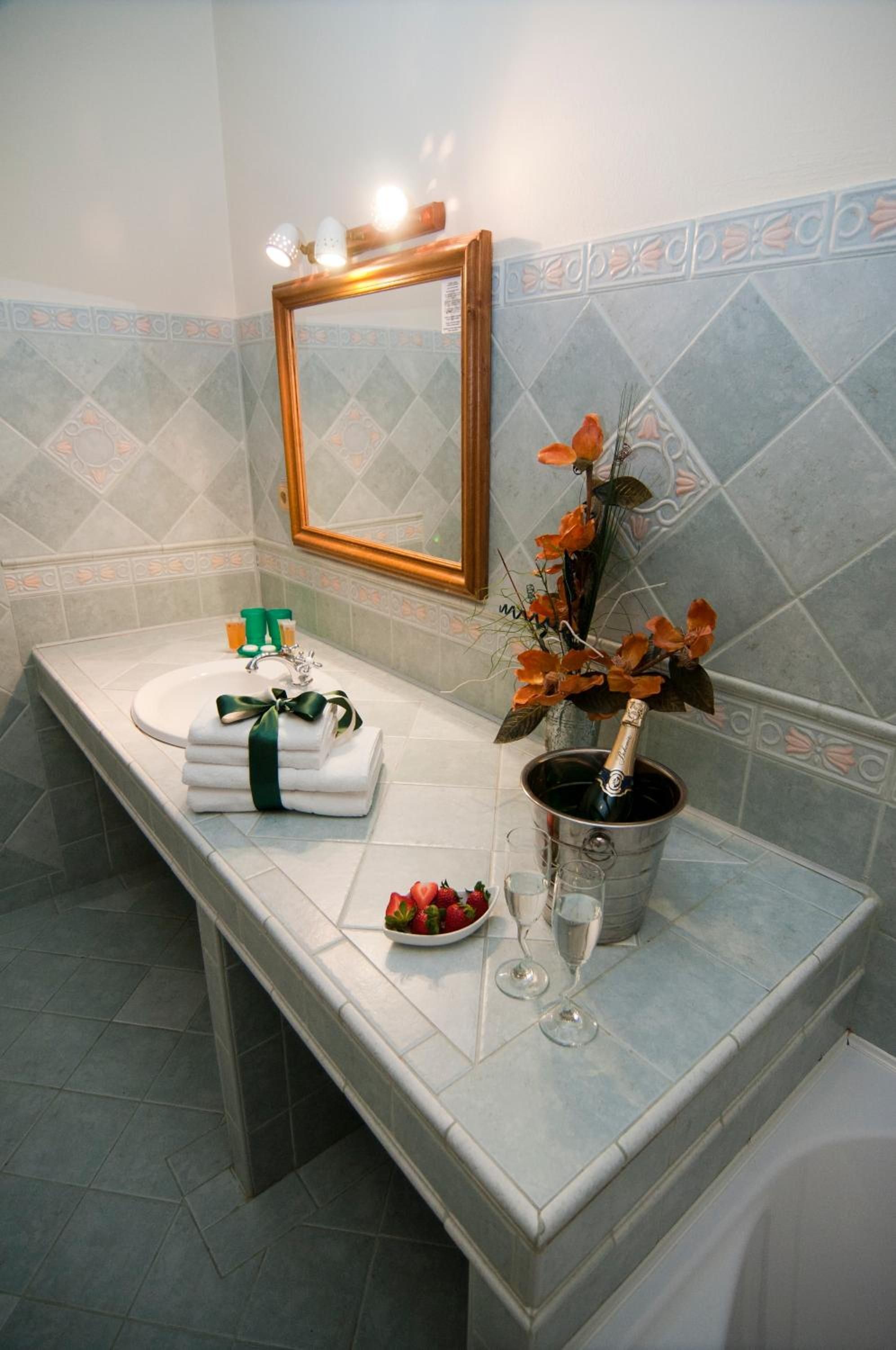 A bathroom with a sink, mirror, and a vase with flowers.
