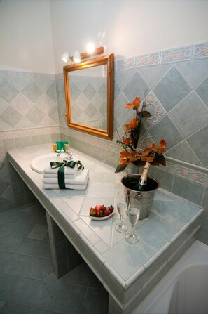 Un bagno con lavandino, specchio e un vaso con fiori.