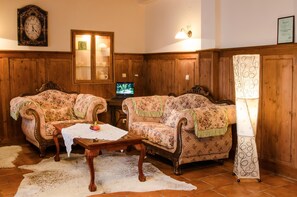 Una camera tradizionale con due divani imbottiti, un tavolino in legno, una televisione e una lampada.