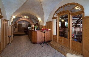 Un'ampia sala con reception in legno, soffitto a volta e un'area bar con vetrine.