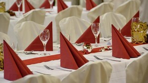 Ein festlich gedeckter Tisch mit weißen Tischdecken, roten Servietten und Besteck.
