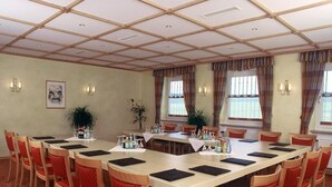 Ein Konferenzraum mit einem langen Tisch, roten Stühlen und einer Holzzahl.