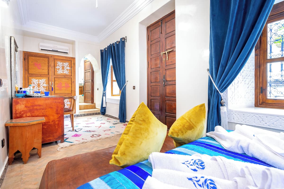 Une chambre d’hôtel avec un lit, un bureau, une chaise et une armoire.
