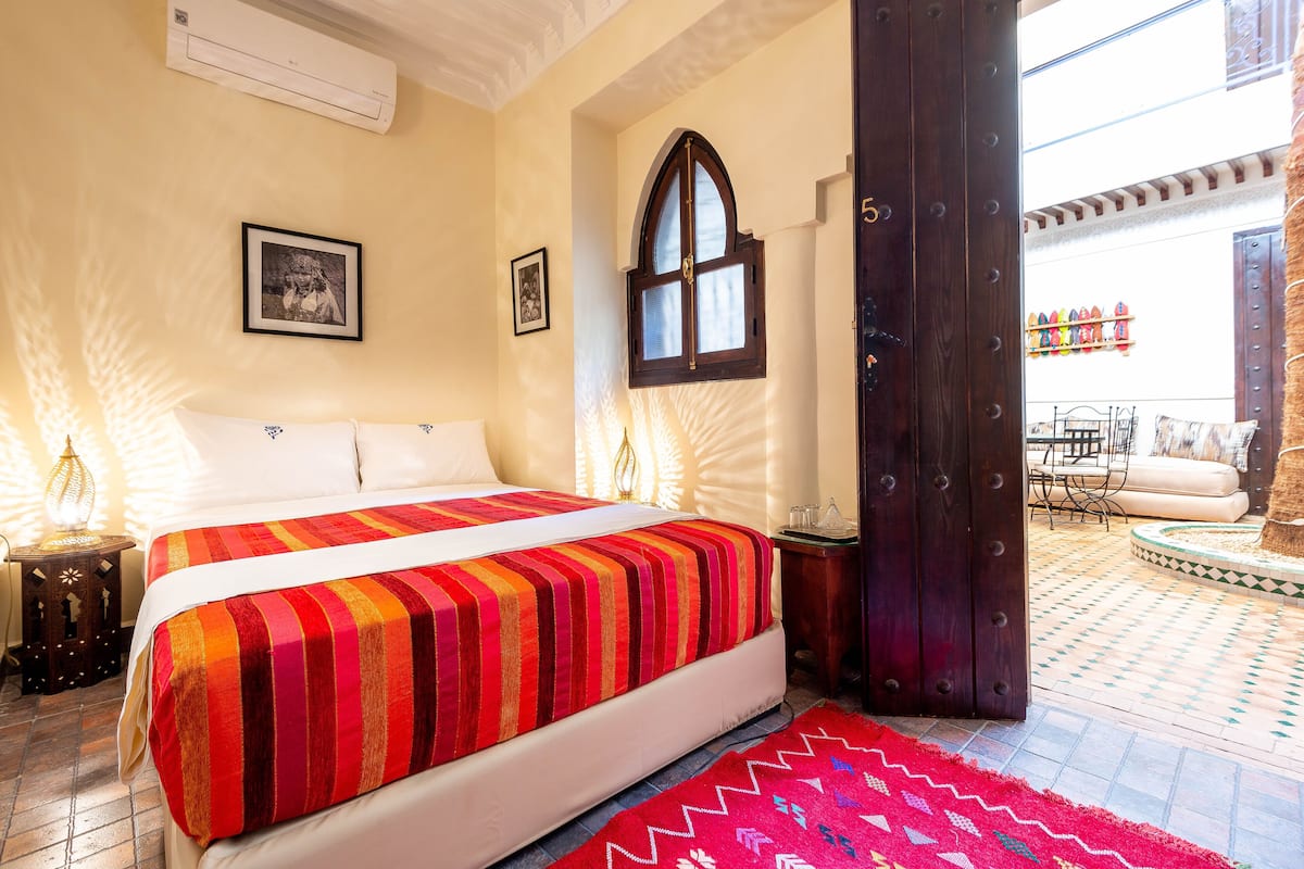 Une chambre d’hôtel avec un grand lit, une fenêtre, une porte et une vue sur la terrasse extérieure.