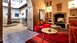 A spacious living area with a high ceiling, a fireplace, and a seating area with a red sofa and a coffee table. - Riad Kamal (Marrakech)