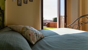 A bedroom with a bed, a pillow, a window, and a door leading to an outdoor area. - Agriturismo El Crear (San Pietro in Cariano)