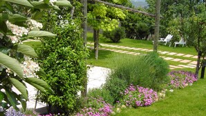 A well-maintained garden with various flowering plants and a stone pathway. - Agriturismo El Crear (San Pietro in Cariano)