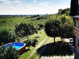 A residential area with a swimming pool, a garden with a paved path, and a view of the countryside.