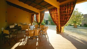 An outdoor patio with wicker furniture and a covered area with curtains. - Ridocco Agriturismo (Campofiorito)