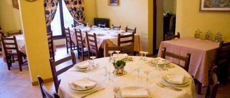 A dining area with round tables set for a meal, chairs, and a window with curtains.