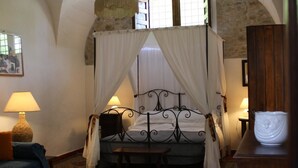 A bedroom with a four-poster bed, a nightstand, a lamp, and a wooden cabinet. - Ridocco Agriturismo (Campofiorito)