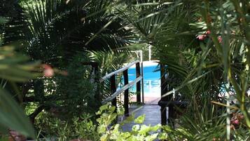 Un pontile in legno conduce a una zona piscina immersa nel verde.