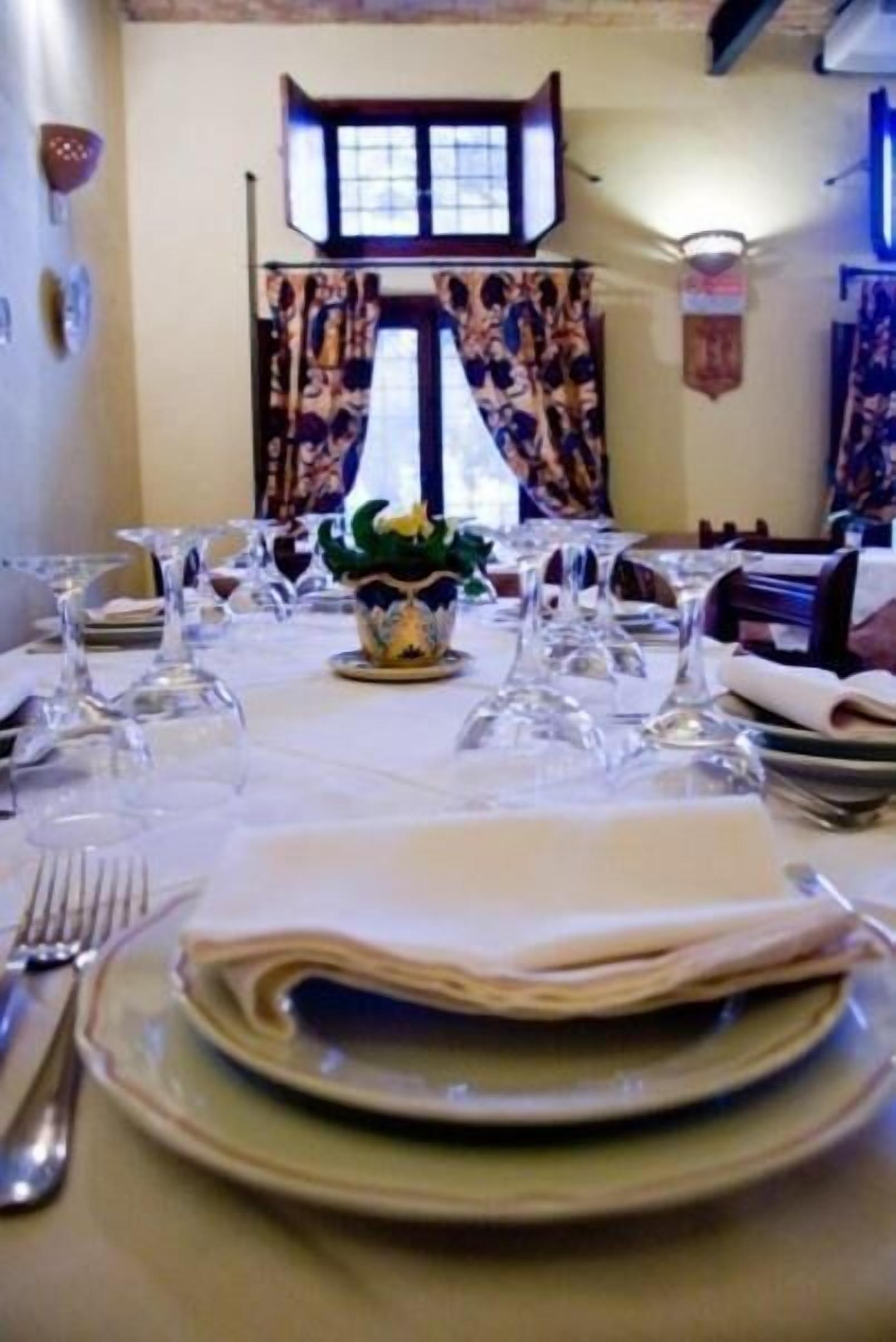 A dining table set with plates, glasses, and cutlery, with a decorative vase in the center.