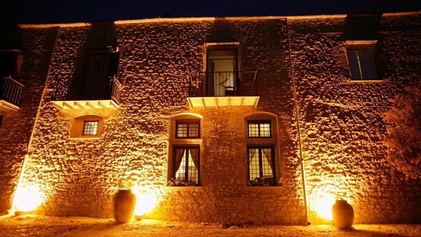 A stone building with two windows and a balcony, illuminated by warm lighting. - Ridocco Agriturismo (Campofiorito)