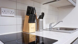 Uma cozinha com uma pia de aço inoxidável, um porta-facas de madeira e um recipiente de metal perfurado.