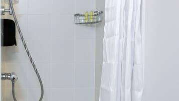 A shower area with a white curtain, a handheld showerhead, and a wall-mounted faucet.