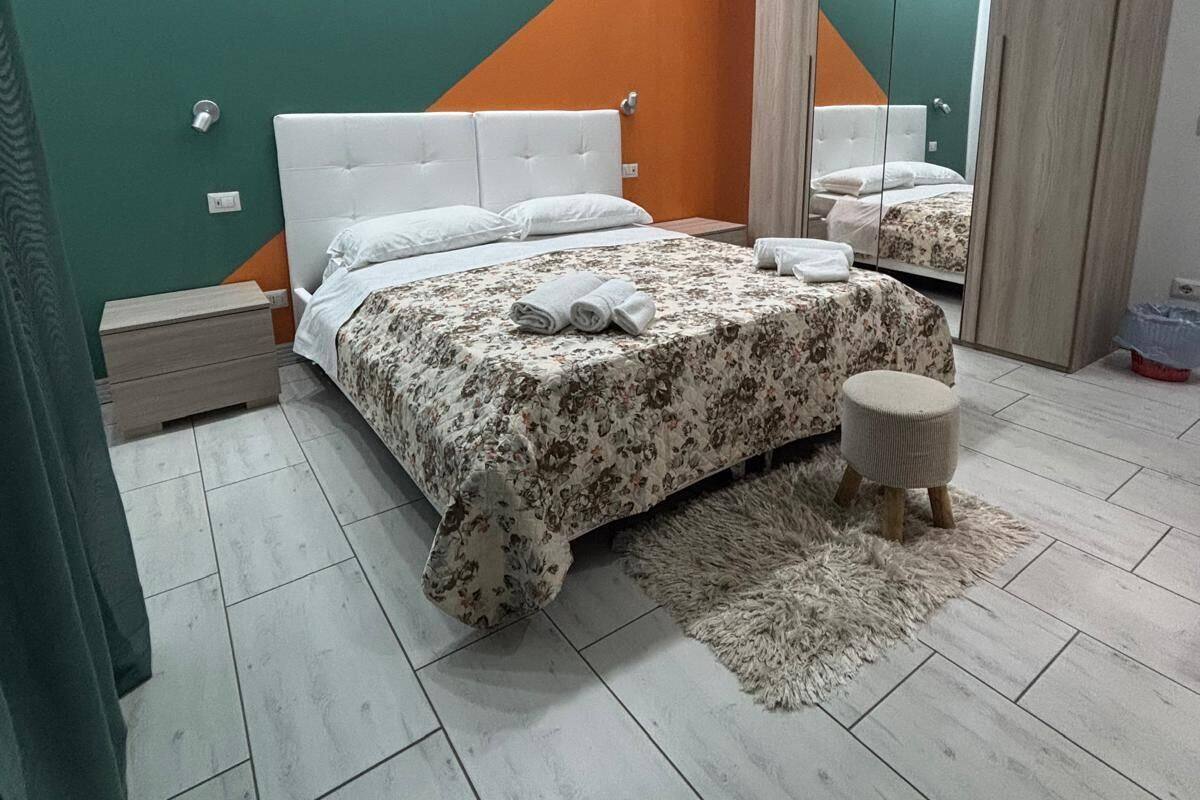 A modern bedroom with a bed, nightstands, a mirror, and a fluffy rug.