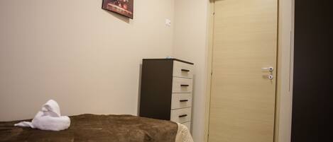 A bedroom with a bed, a wardrobe, a door, and a painting on the wall.
