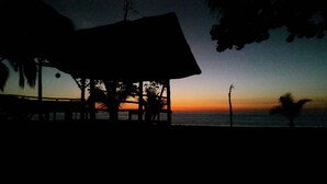 A beachside hut with a view of the ocean at sunset. - Jonny's cabins drake day (Drake Bay)