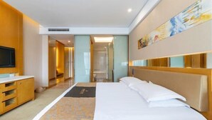 A hotel room with a bed, a TV, a wooden cabinet, and a bathroom visible through an open door. - Jialuan International Hotel (Taizhou)
