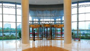 A spacious lobby with a glass entrance, large columns, and a view of the cityscape. - Jialuan International Hotel (Taizhou)