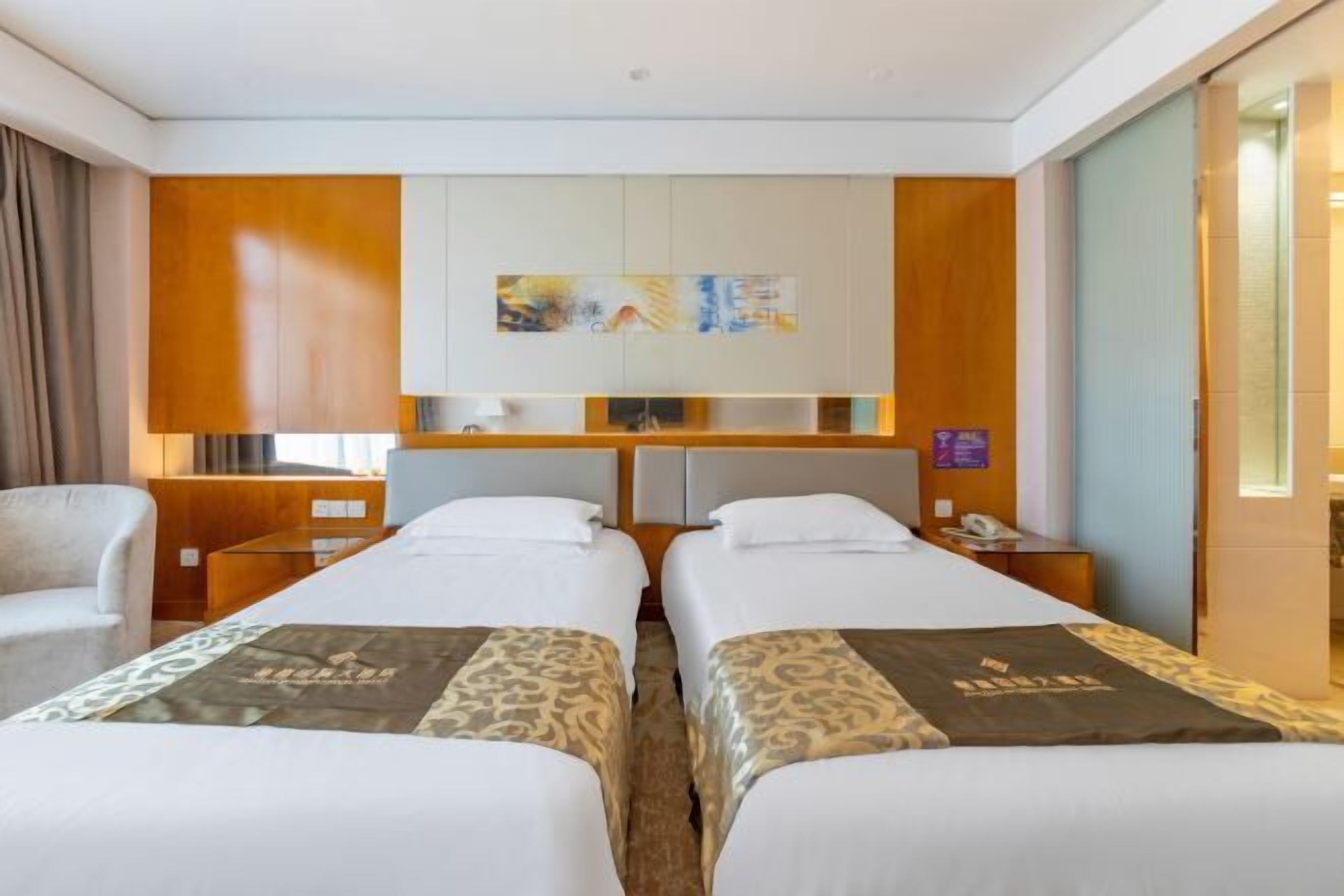 Ein Hotelzimmer mit zwei Betten, einem Schreibtisch, einem Stuhl und einem Bild an der Wand.