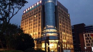 A multi-story hotel with a curved glass facade and illuminated signage. - Jialuan International Hotel (Taizhou)