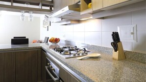 Una cocina moderna con armarios de madera, encimera de granito, estufa a gas y un juego de cuchillos.
