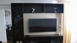 Un centro de entretenimiento moderno con un televisor de pantalla plana grande, estantes integrados y un pequeño adorno en el estante superior.