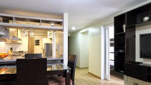 Una cocina moderna con una mesa de comedor y sillas, un televisor montado en la pared, y un pasillo que conduce a otra habitación.