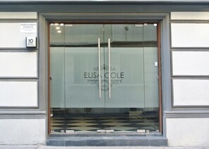 A hotel entrance with a glass door, a sign indicating a 10-room hotel, and a sign for alcohol beverage expenses. - Hotel Elisa Cole (Santiago)