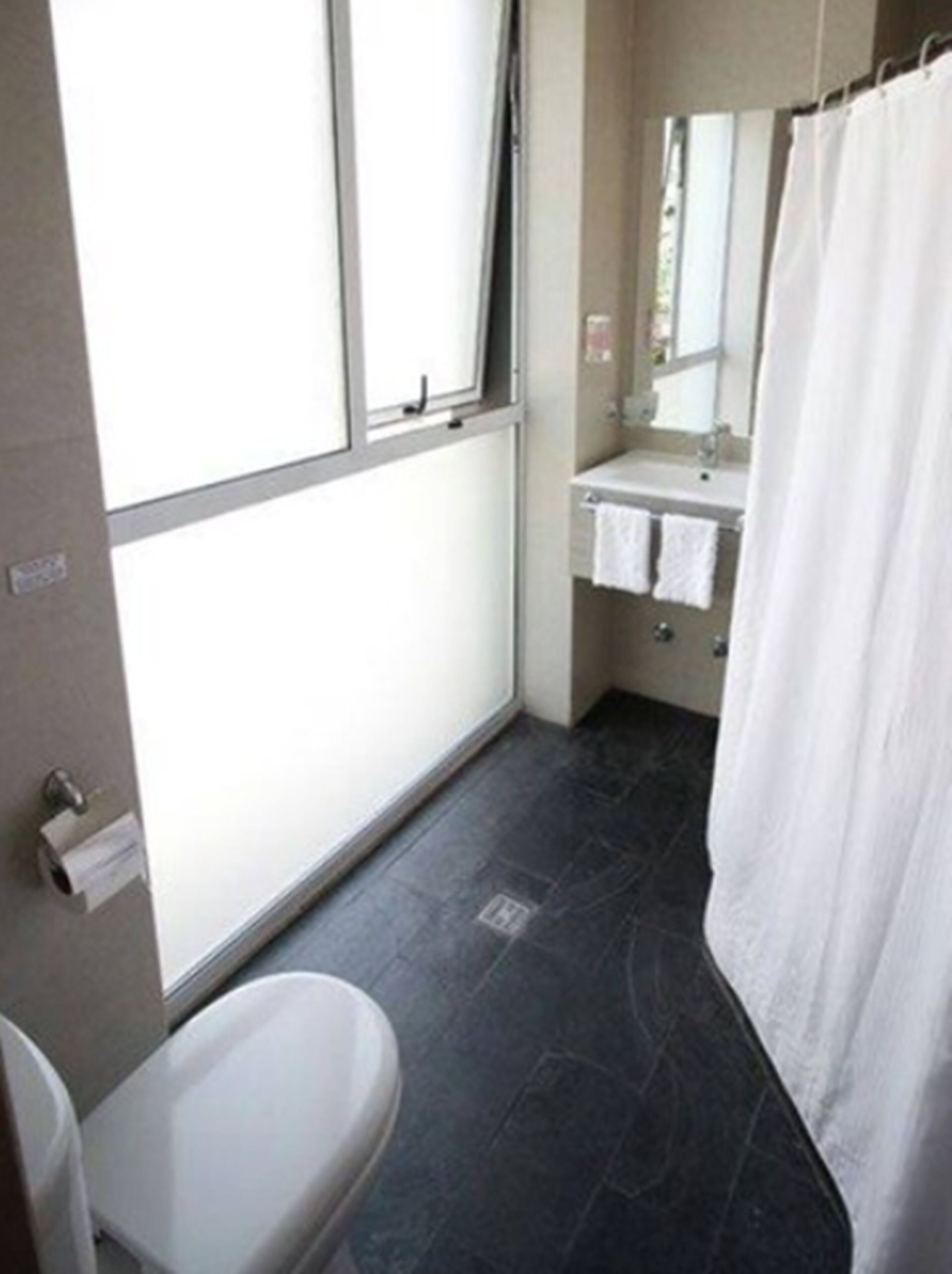 A bathroom with a toilet, sink, and shower curtain.
