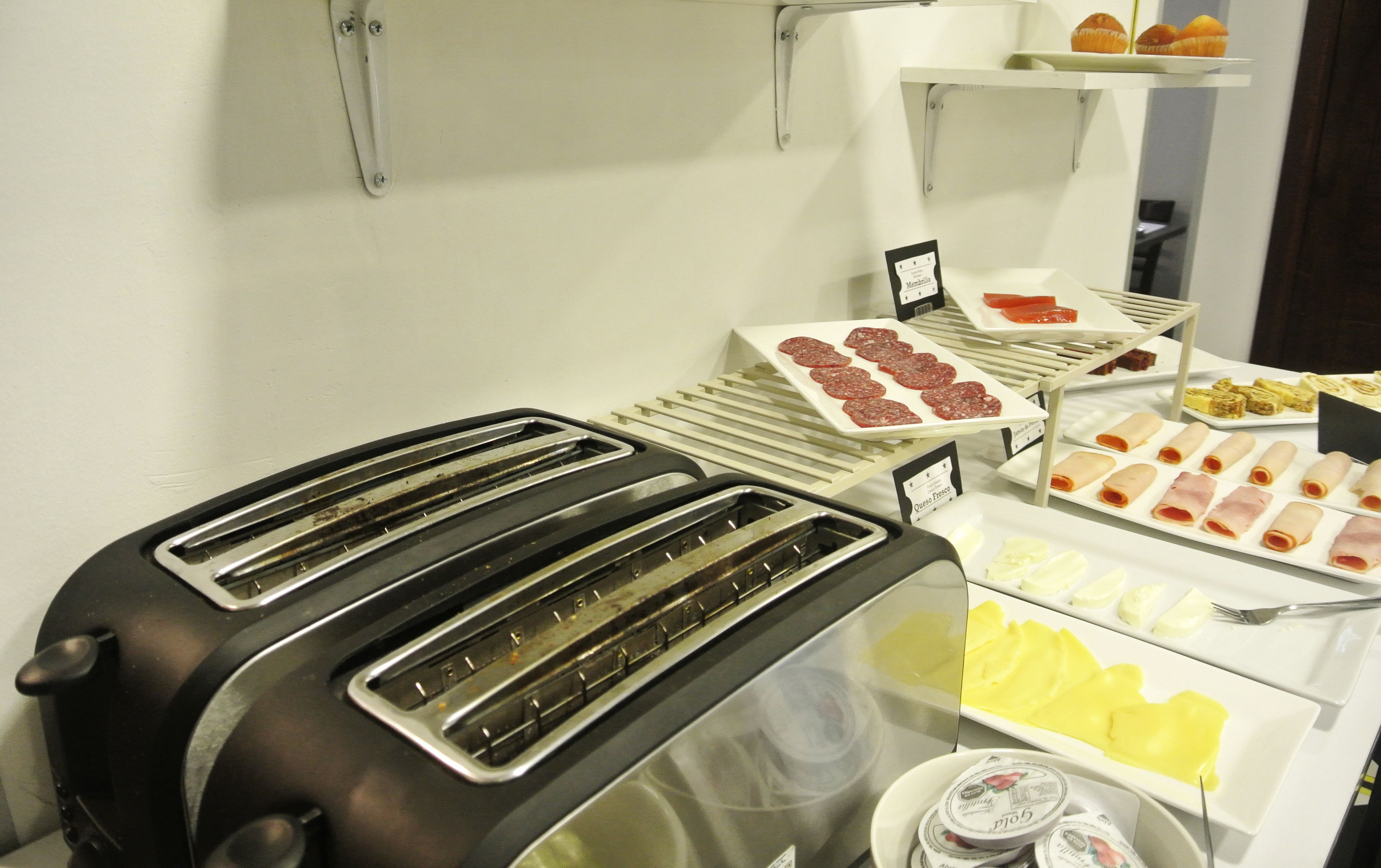 A buffet with various food items including sliced meats, cheeses, and pastries.