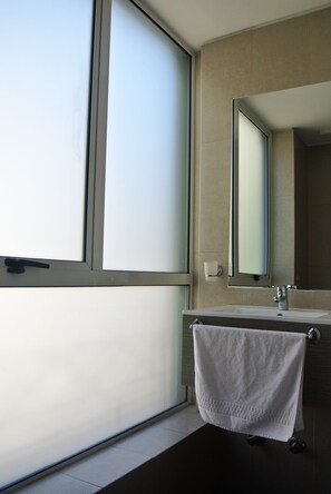 A bathroom with a large window, a sink, and a towel hanging on a rack. - Hotel Elisa Cole (Santiago)