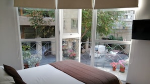 Un dormitorio con cama, ventana y vista a la calle.