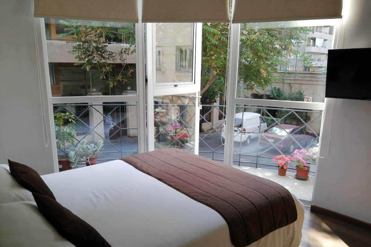 Ein Schlafzimmer mit Bett, Fenster und Blick auf die Straße.