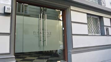 La entrada del Hotel Elisa Cole, con una puerta de cristal y un piso con estampado de cuadros.
