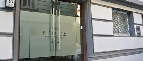 The entrance to Elisa Cole Hotel with a glass door and a checkered floor pattern.