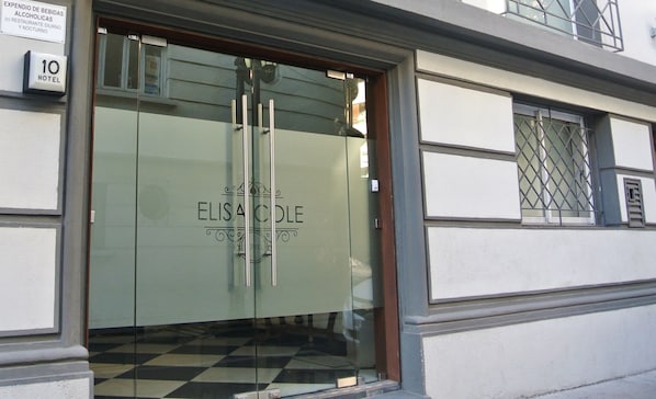 The entrance to Elisa Cole Hotel with a glass door and a checkered floor pattern.