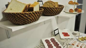 Una exhibición de panes y pasteles sobre una estantería blanca.