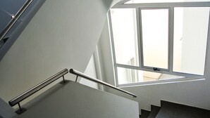 Una escalera moderna con barandilla metálica que lleva a un rellano con un amplio ventanal.